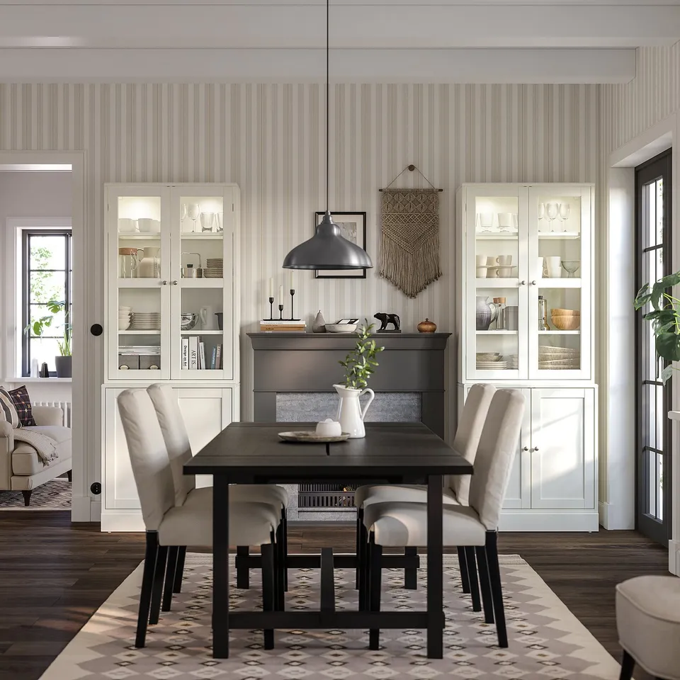 Modern dining room with HAVSTA cabinets, dark table, beige chairs, black pendant lamp, striped wallpaper.