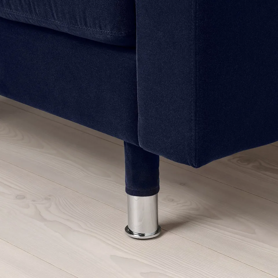 Close-up of a dark blue sofa with metal legs on wooden floor.