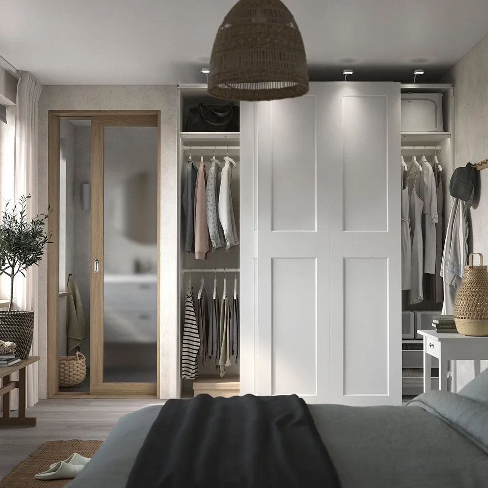 Bedroom with open wardrobe showing clothes and storage; grey bedheet.