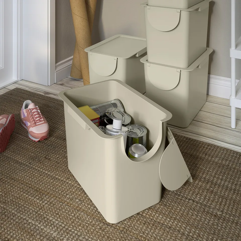 Three beige TRÖSKNING bins, with the front one open showing recycling items inside. Stacked for space-saving and sorting waste.