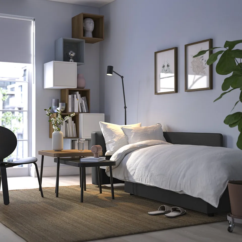 Modern bedroom with SKÖNABÄCK sofa bed and bookshelf.