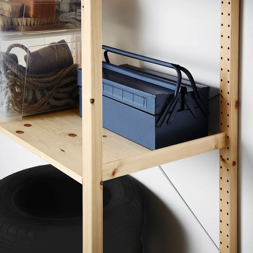 Wooden shelf unit storing metal toolbox and tyre.