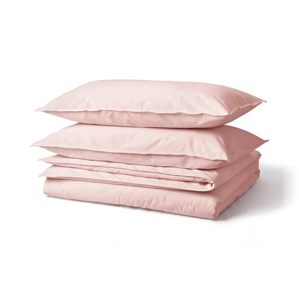 Three folded pink cotton duvet covers, neatly stacked, soft and inviting, perfect for a cosy bedroom.