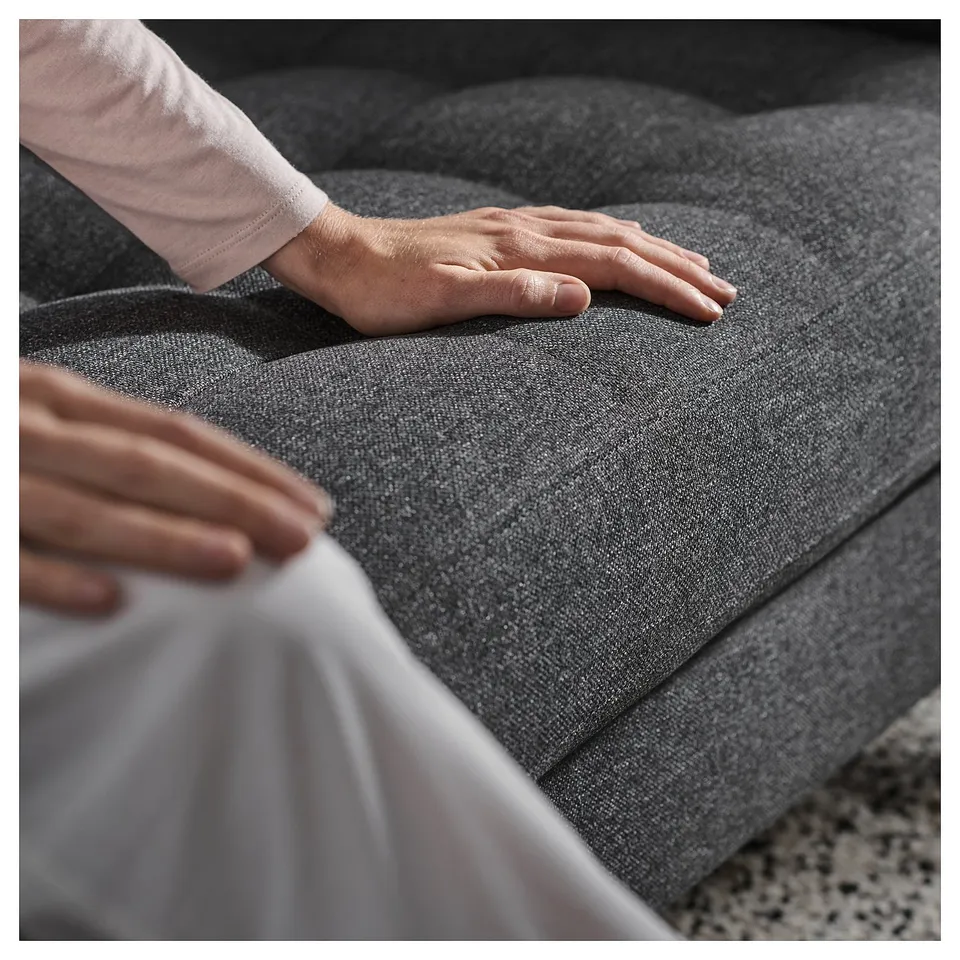 Person adjusting grey fabric sofa cushion. Comfortable and modern design.