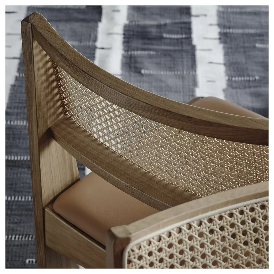 Modern chair with light wood frame and woven natural rattan back, tan leather seat.