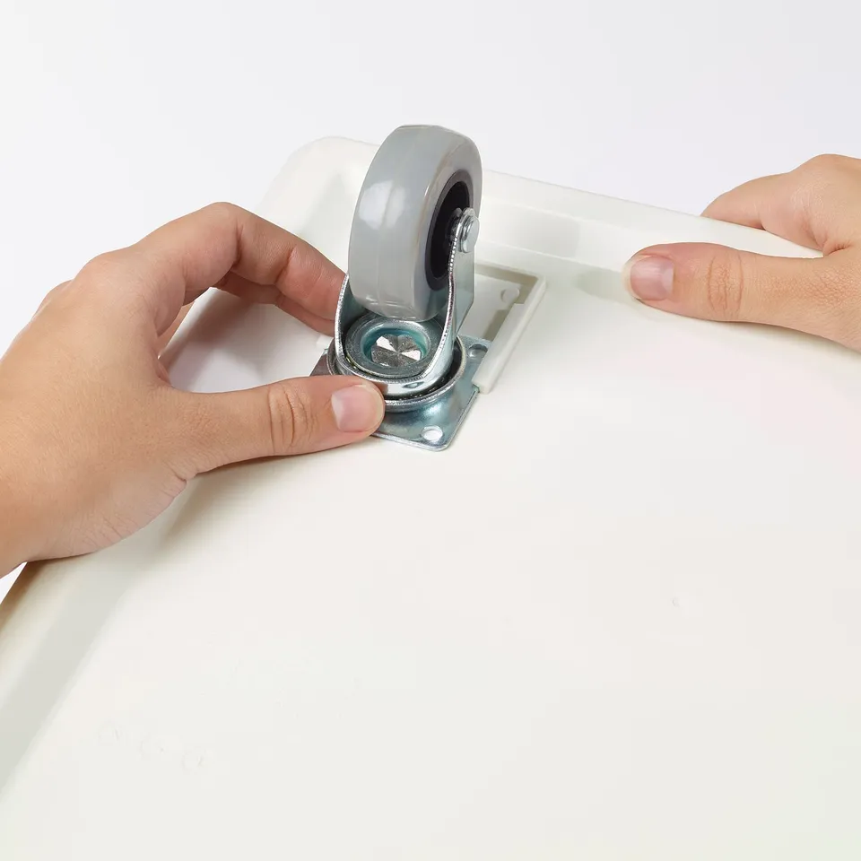 Attaching wheels to a white box for mobility.