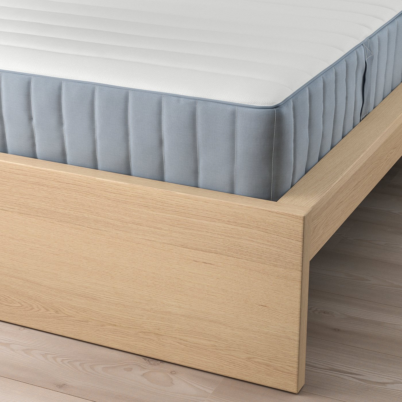 A light wooden bed frame with a light-colored mattress. The slatted base supports the mattress, providing comfort and air circulation.