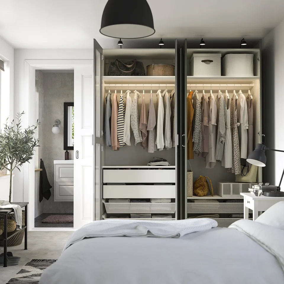 A modern bedroom with an open wardrobe showing clothes and storage, mirrored doors.