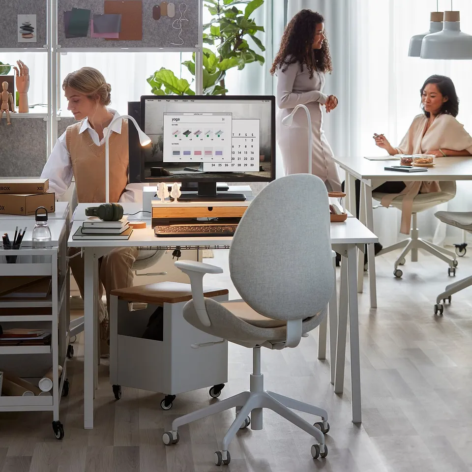 Three people working at modern TROTTEN desks in an office.