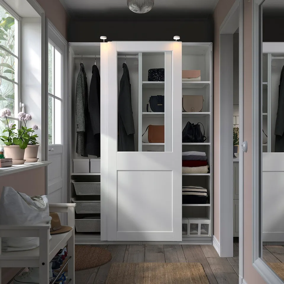 White PAX wardrobe with glass doors displays clothes and accessories neatly.