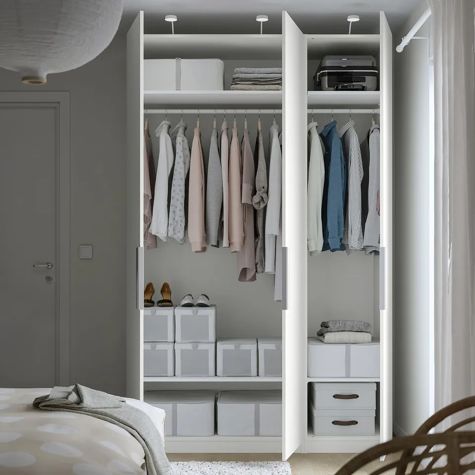 A modern, white, open closet displaying clothes and storage solutions, with socks on shelves and boxes for organisation.