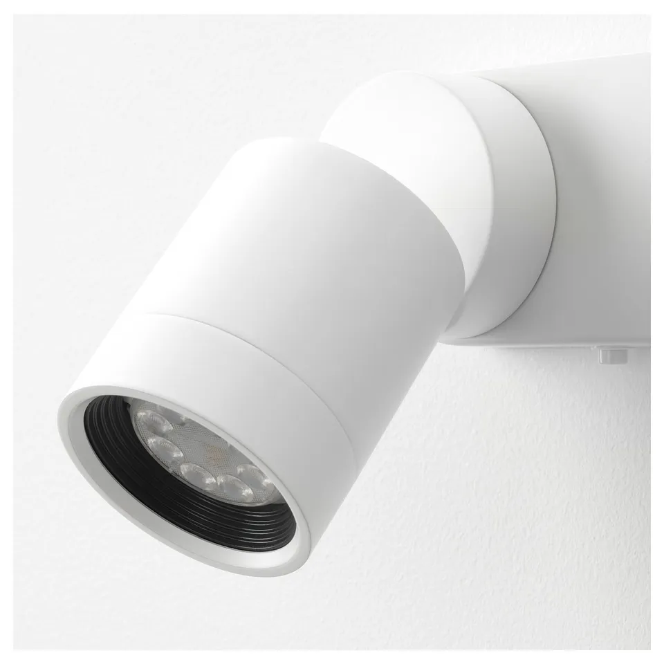 White wall-mounted adjustable light fixture with multiple leds inside a cylindrical black inner shade, securely attached to a white base.