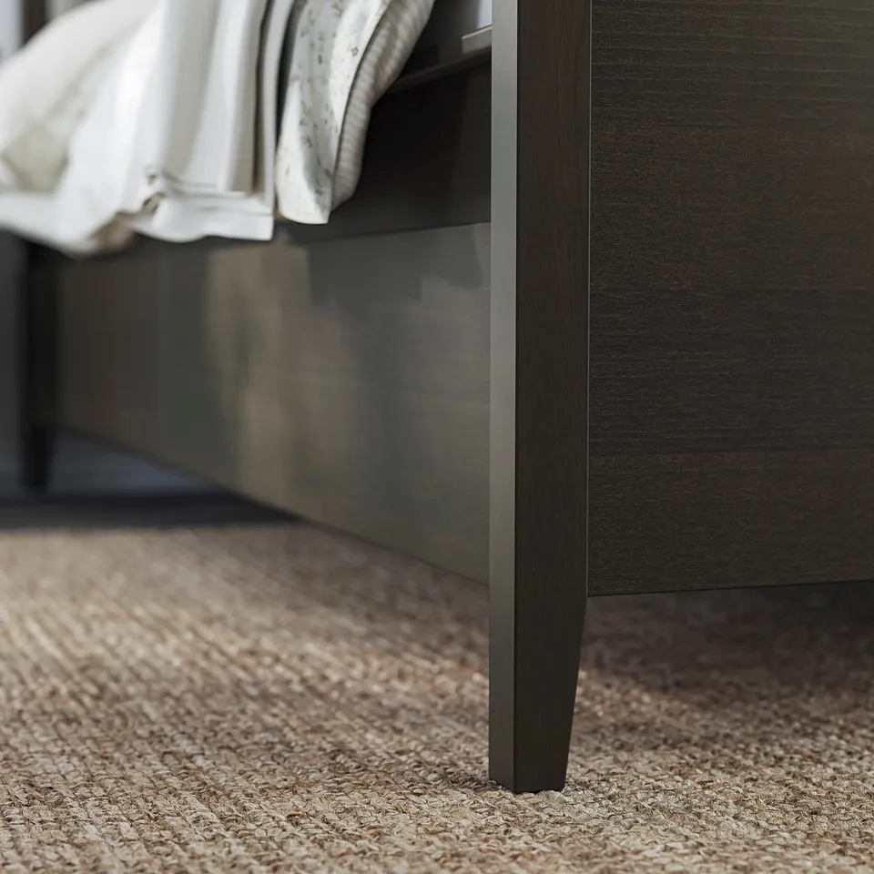 Dark wood IDANÄS bed frame with drawers, fabric curtain, beige rug.