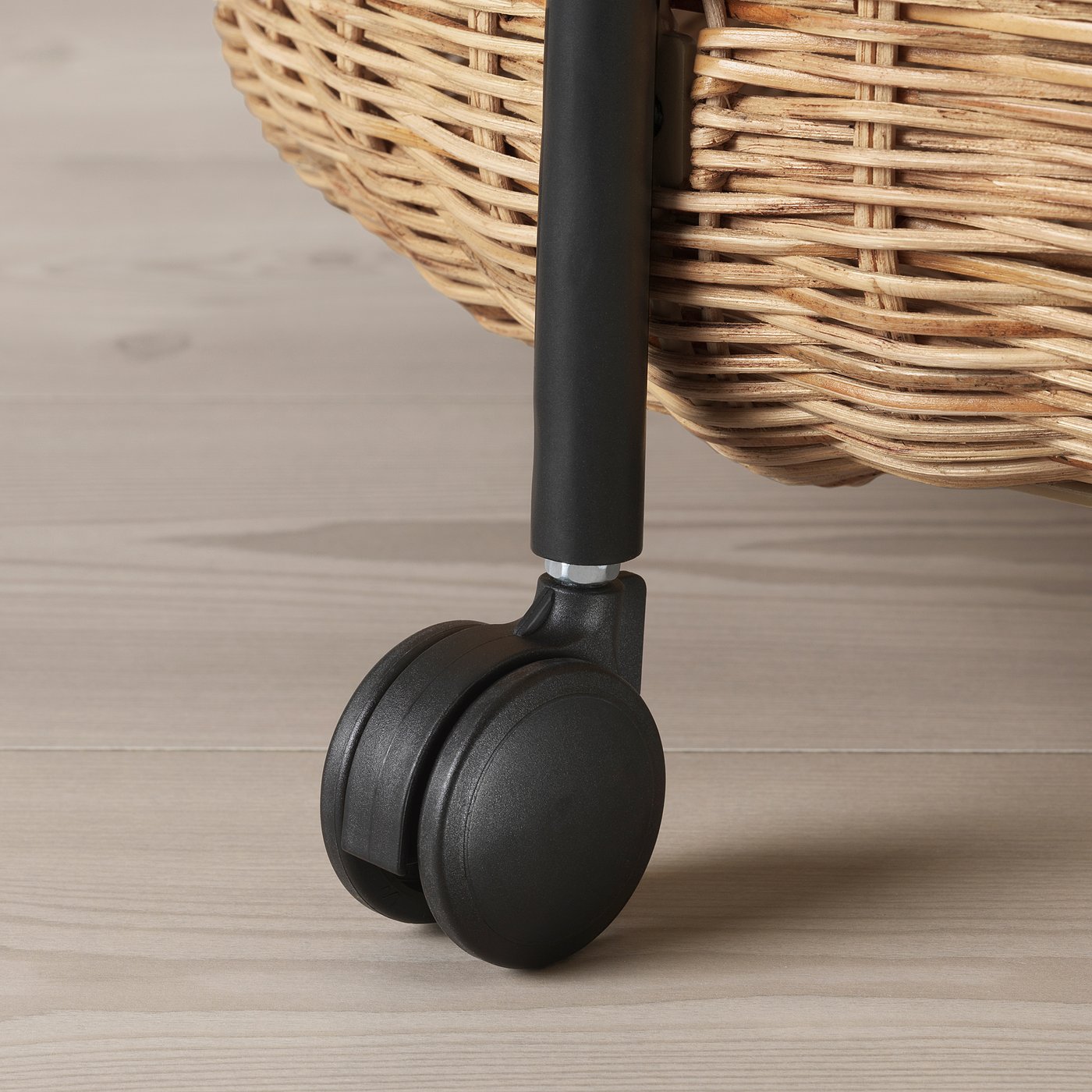 Close-up of wicker basket trolley with sturdy black wheel.