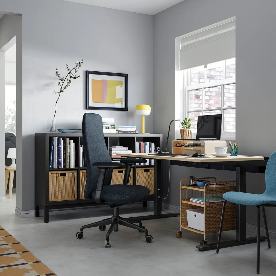 Modern grey home office setup with MITTZON desk, ergonomic chair, bookshelf, and computer equipment.