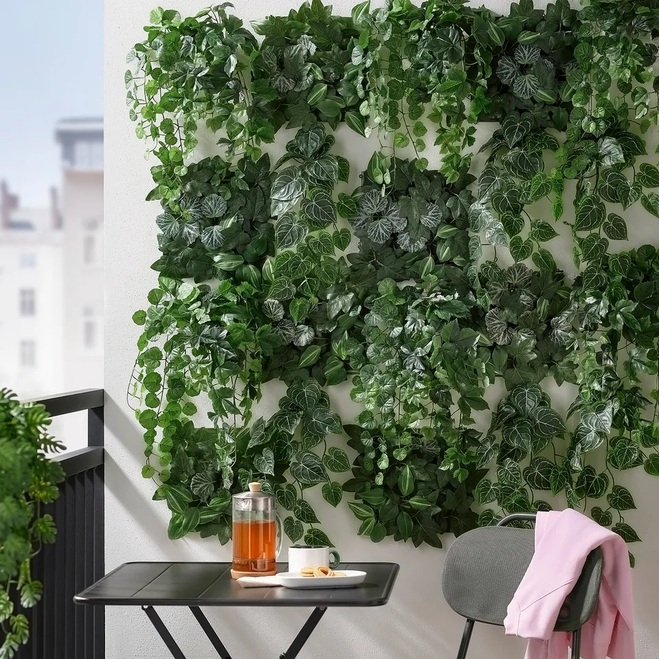 Balcony with green wall, tea setup, pink sweater, city view