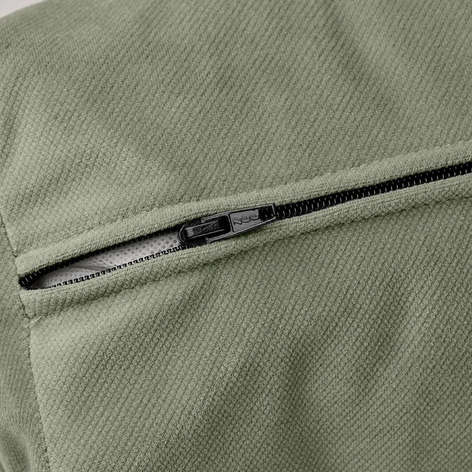 Close-up of a soft, textured light green fabric with a partially open zip showing quality stitching.