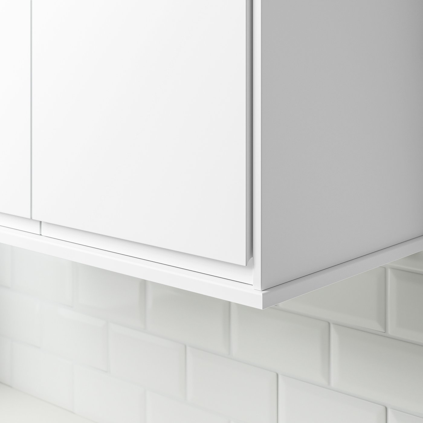 White cabinet trim installed under a kitchen cabinet, concealing lighting and cords, showcasing its functional design.