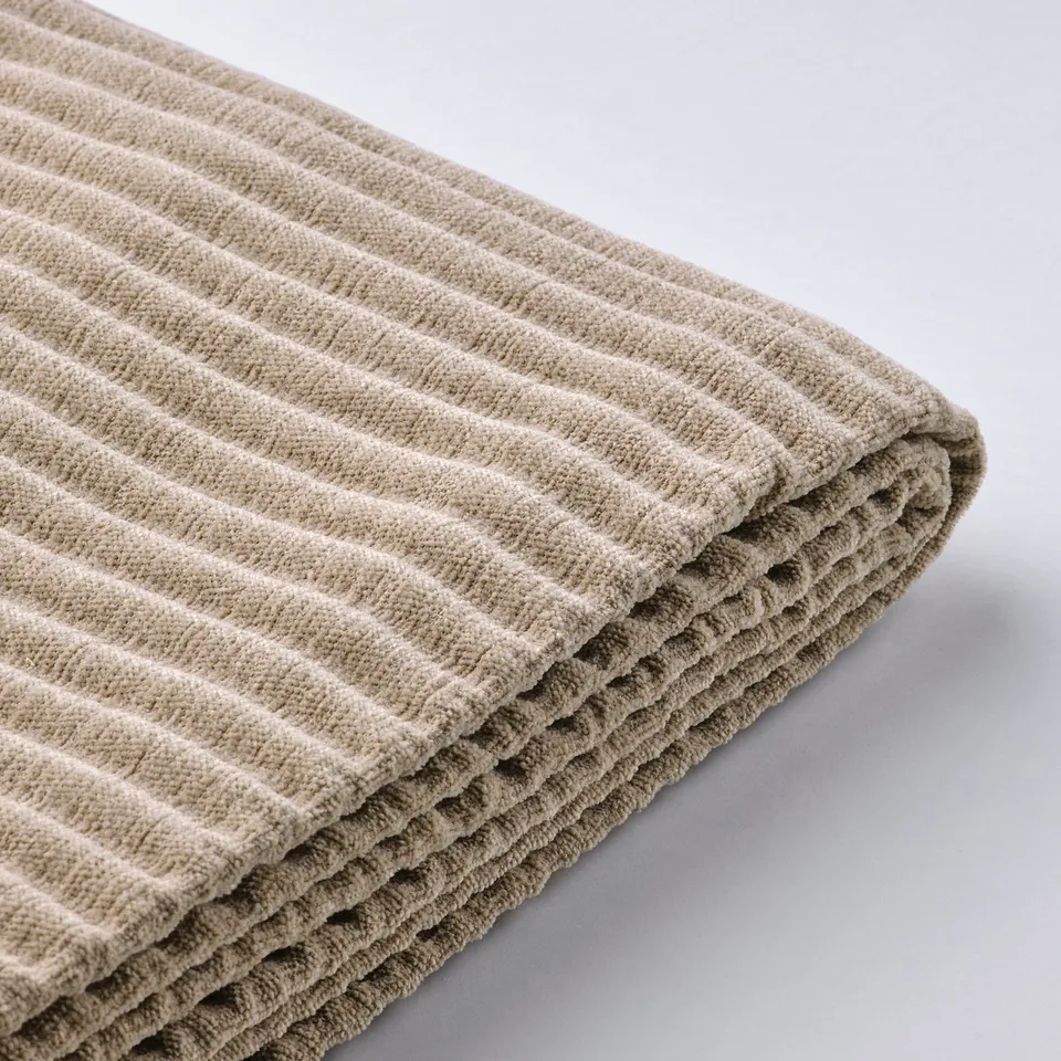 Folded beige textile, waffle pattern. Soft, high-quality fabric, neatly stacked.