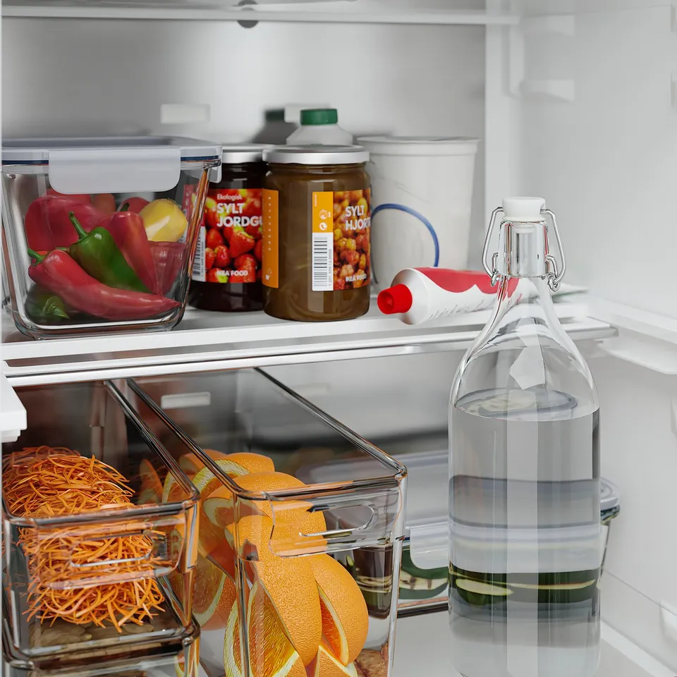 Open fridge with peppers, pickles, oranges, carrots, water bottle.