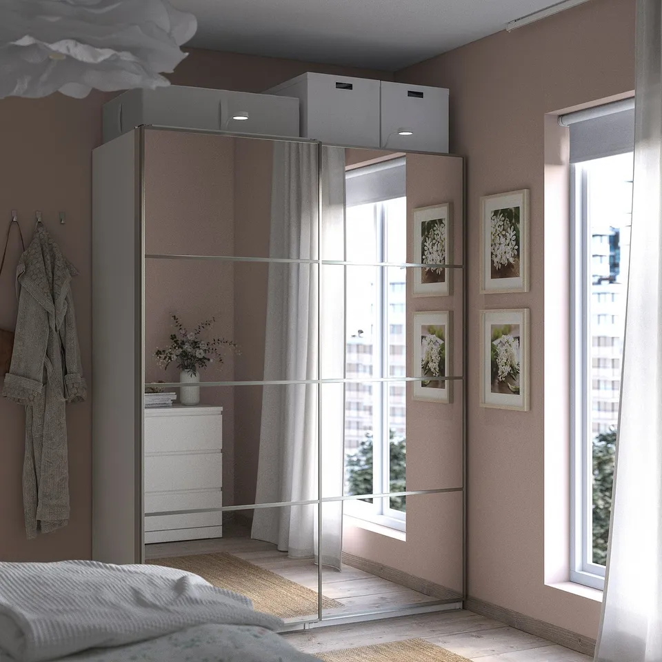 Modern bedroom with large mirrored wardrobe, white bed, wall art, and large window.