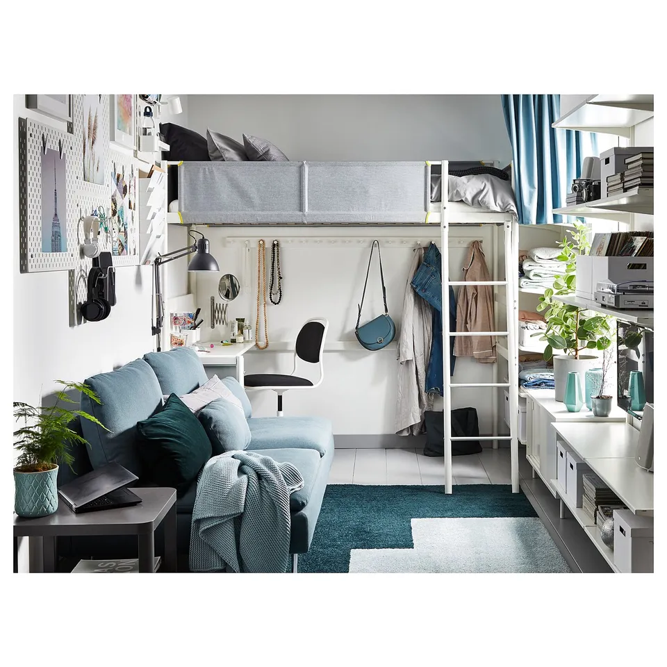 Small cosy dorm room with loft bed, desk, and couch. Blue and white decor, plants, and personal items.