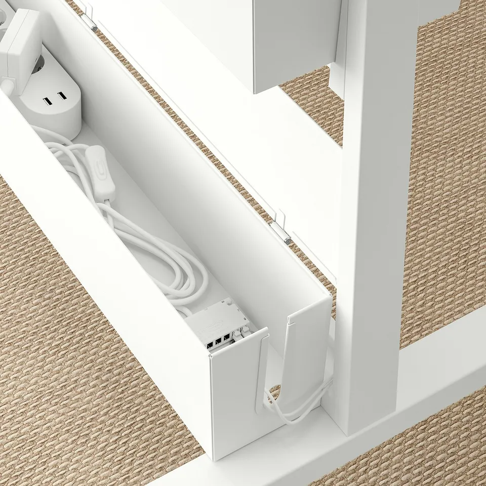 White MITTZON cable box with power outlets and cord, mounted on beige woven floor.
