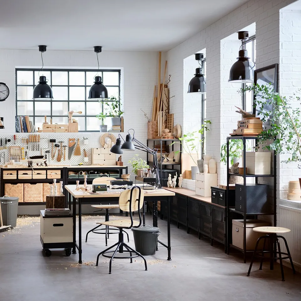 Home office with KULLABERG desk, black and natural wood, industrial style, large window, plants, shelves, and seating area.