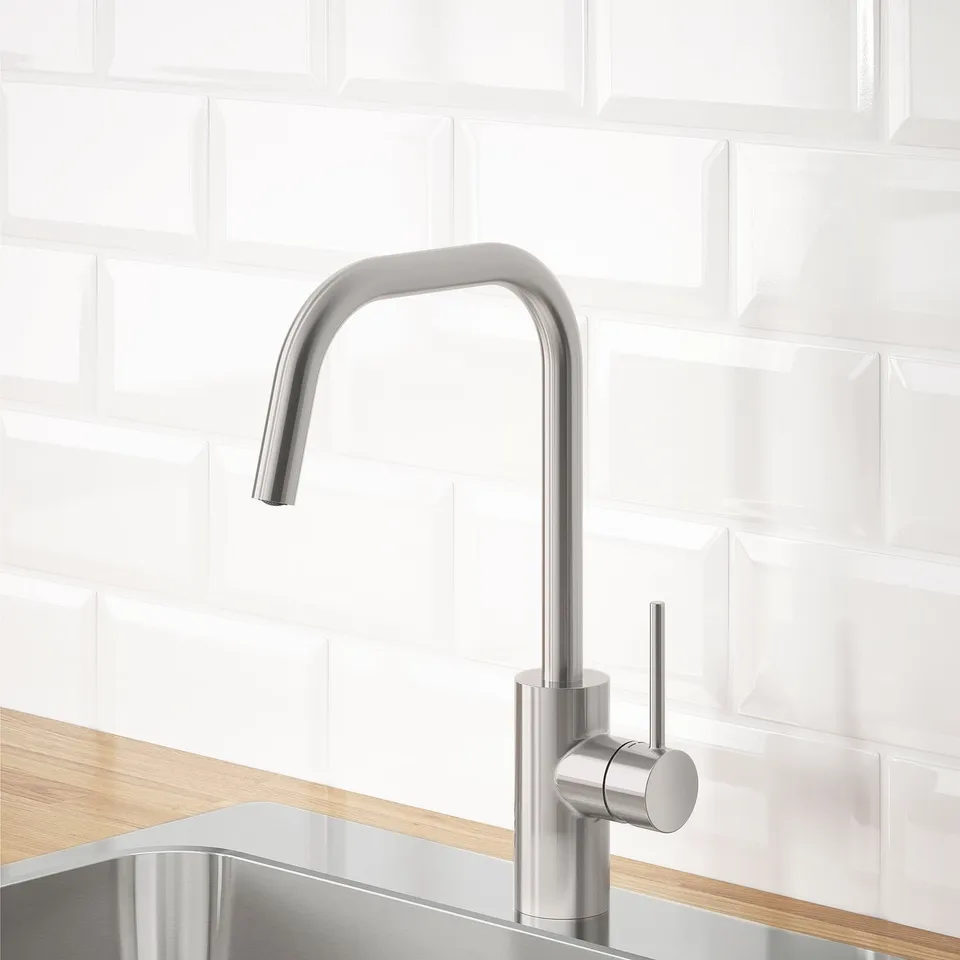 Stainless steel tap with a high arch spout, mounted on a sink, set against a white tiled wall, demonstrating water efficiency.