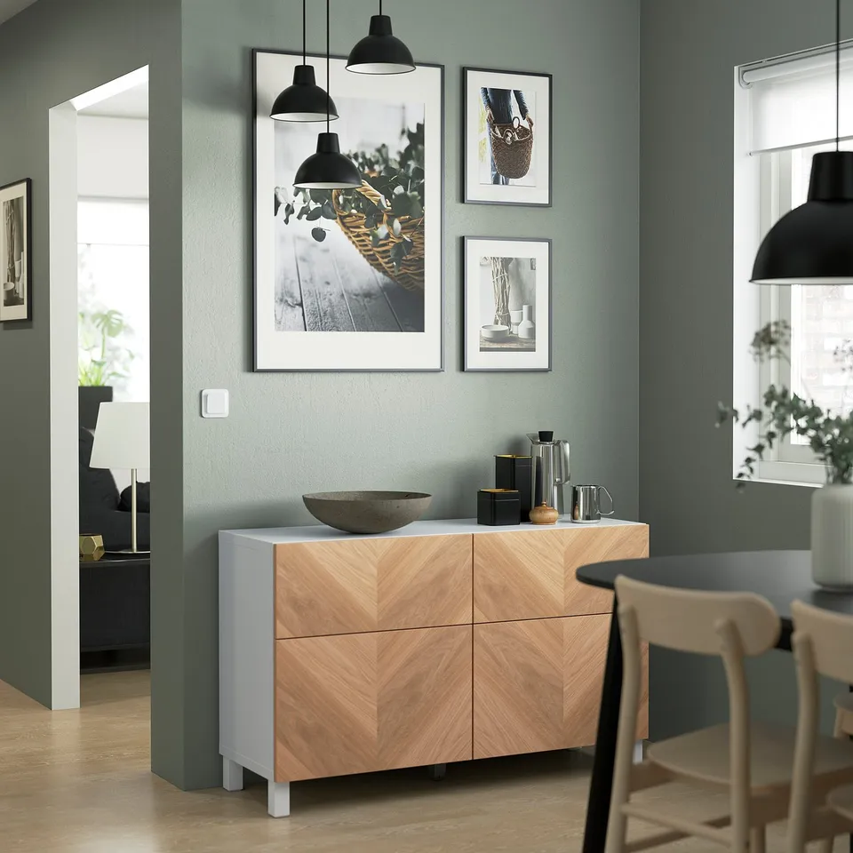 Modern room with BESTÅ sideboard, green wall, decor, lamps, chair, plant, window.