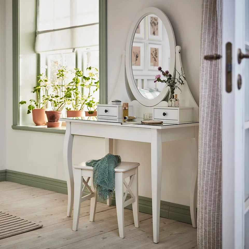 Bright room with white HEMNES vanity, mirror, plants, and curtained window.