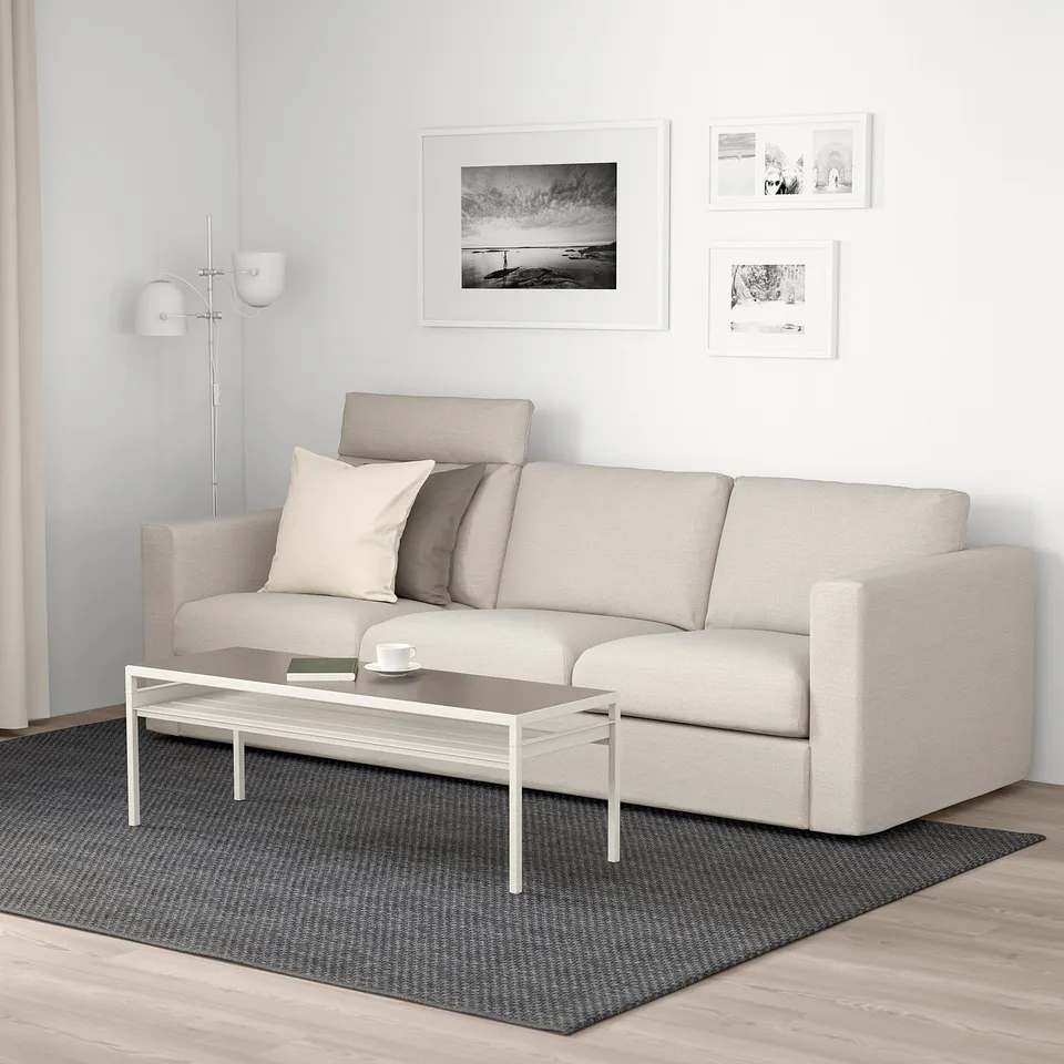Modern living room with grey VIMLE sofa, coffee table, dark rug, art, and floor lamp.