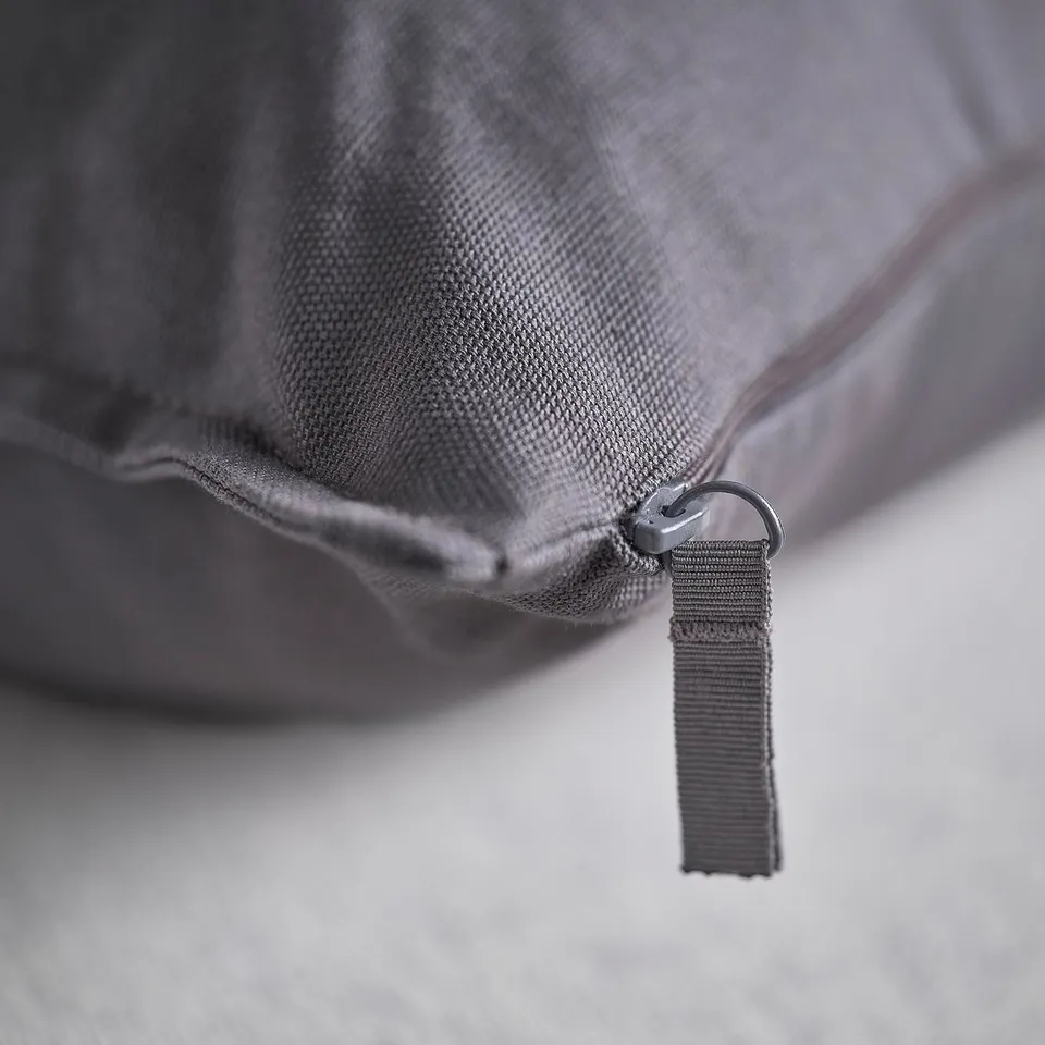 Close-up of a durable, grey cushion cover made from eco-friendly cotton. A sturdy zip for easy removal.