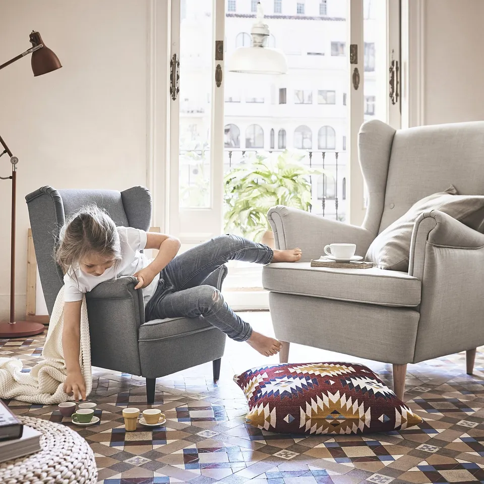 Girl in childs armchair, mini tea set, city view.