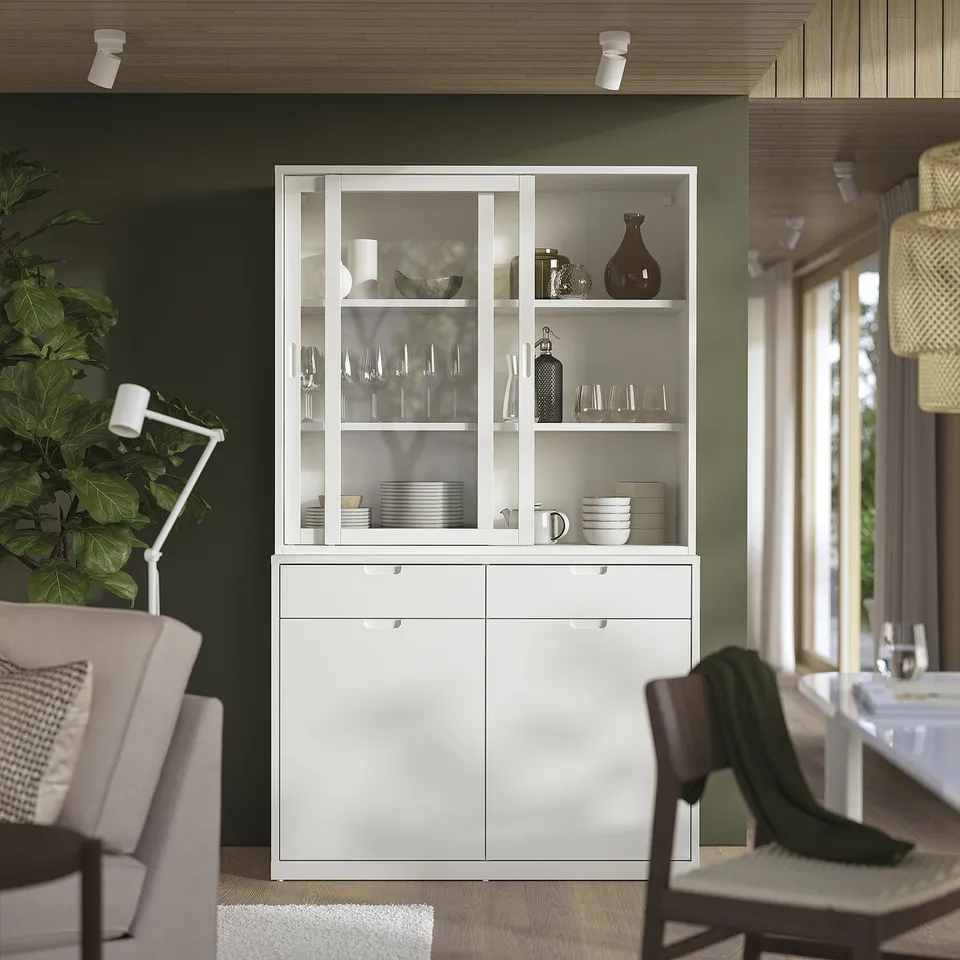 Modern dining room with TONSTAD white cabinet, glass doors, dishes, chairs, and plant.