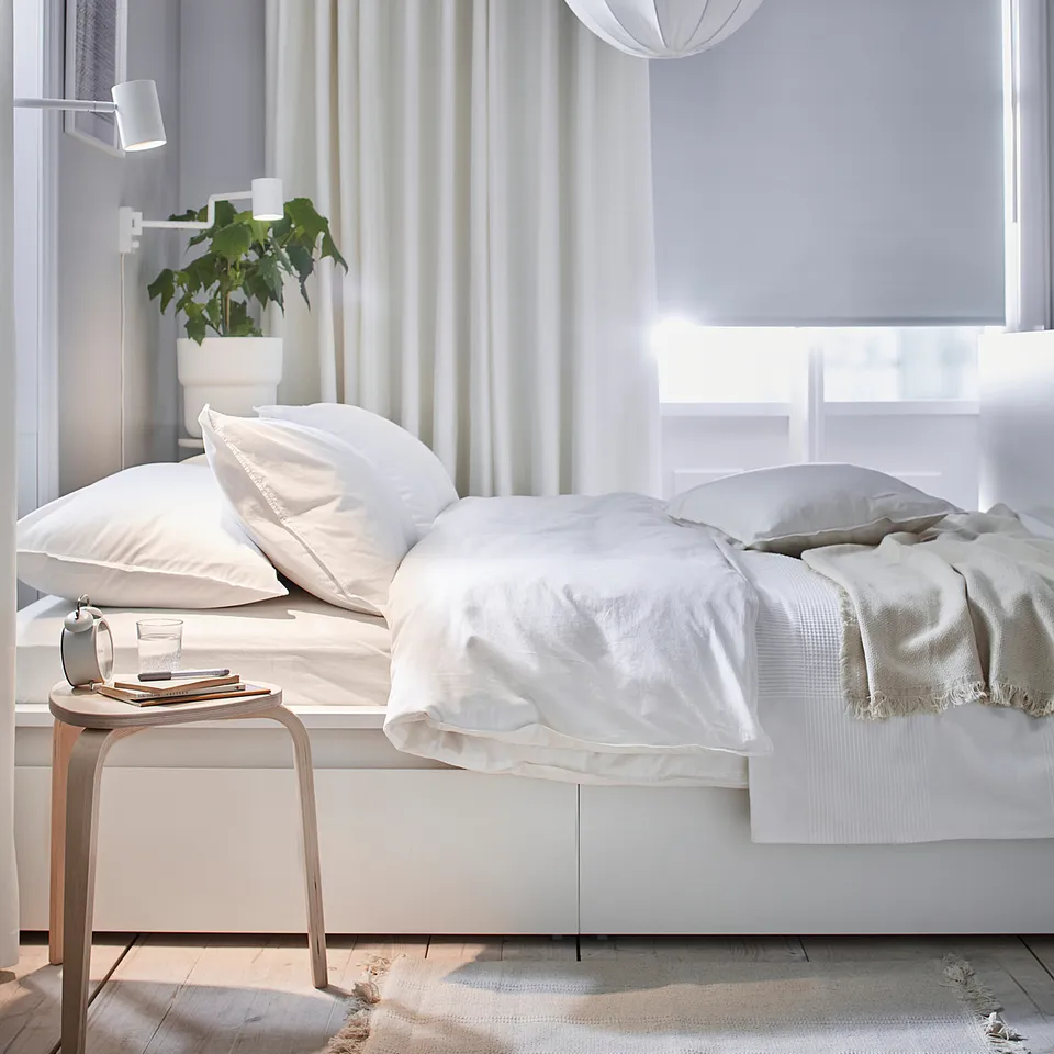 Minimalist white bedroom MERETE cotton room-darkening curtains, white bedding, pendant light, and plant.