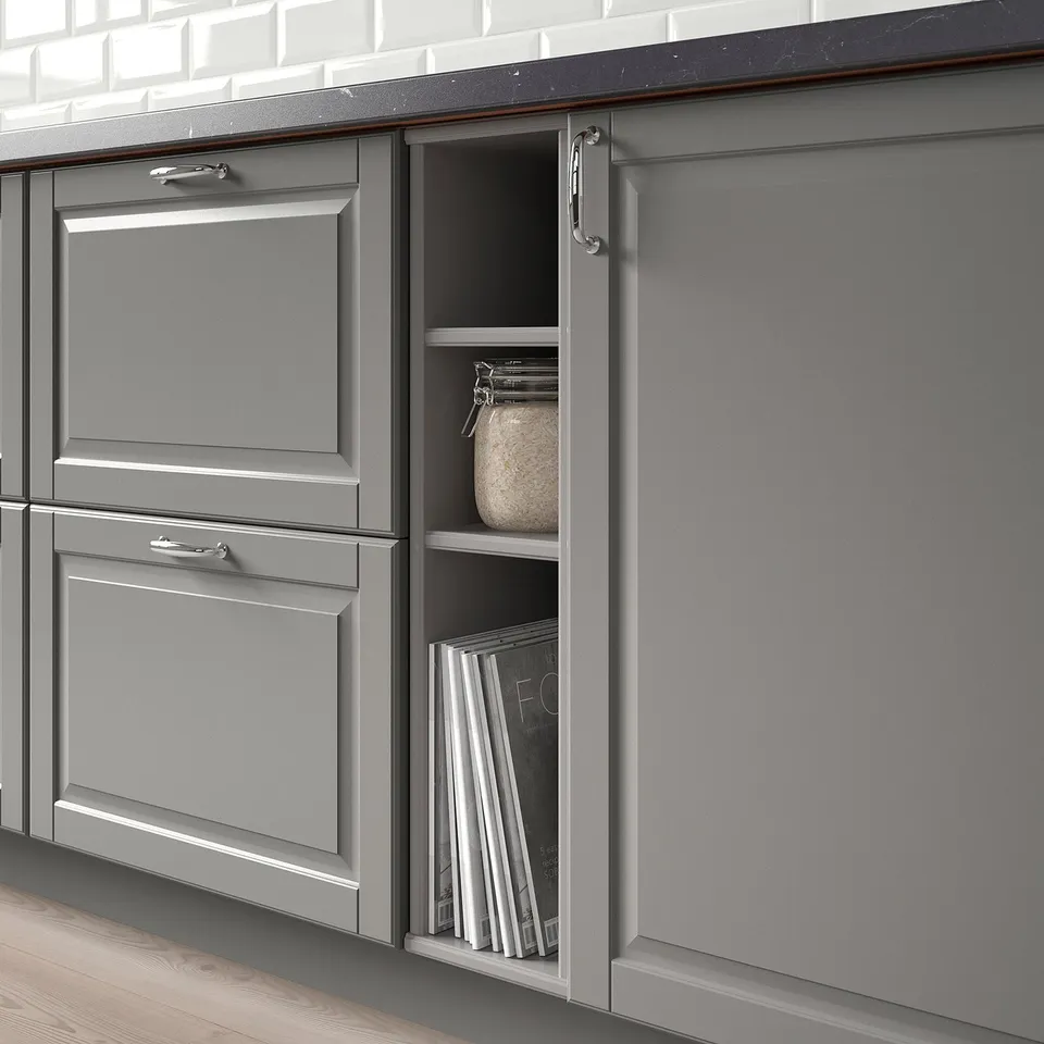Grey kitchen cabinets display open section showing cookbooks and jar, demonstrating organised storage of kitchen items.