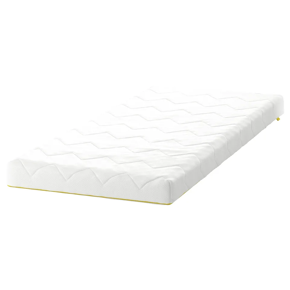 An a white UNDERLIG junior mattress with yellow trim, rectangular shape, textured pattern, and soft foam filling.