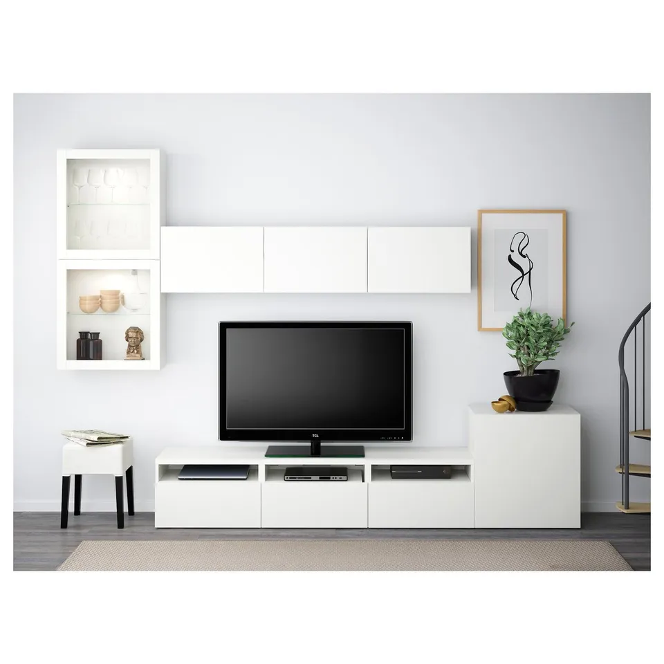 Modern living room with white BESTÅ tv storage. Flat-screen tv on wide stand, wall shelves, and drawers, providing ample storage and cable management.