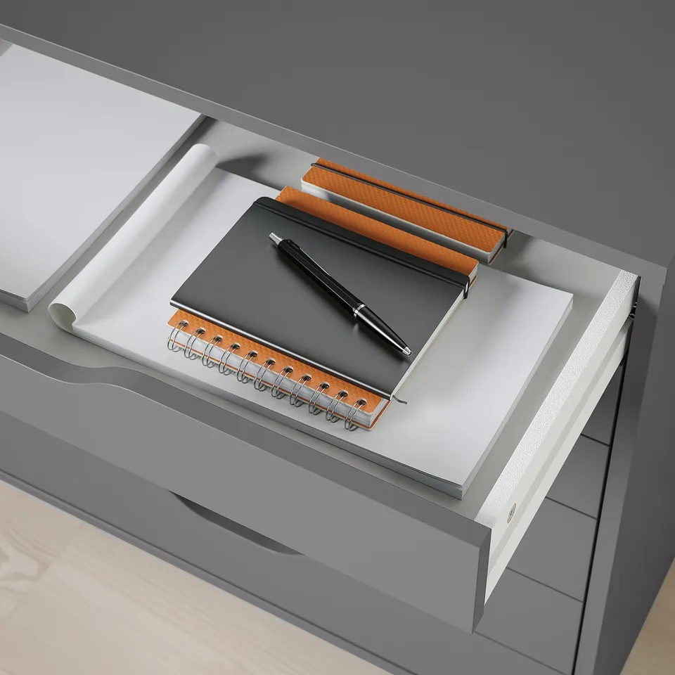 Open desk drawer with notebook, pen, and notepad, ready for study or work.