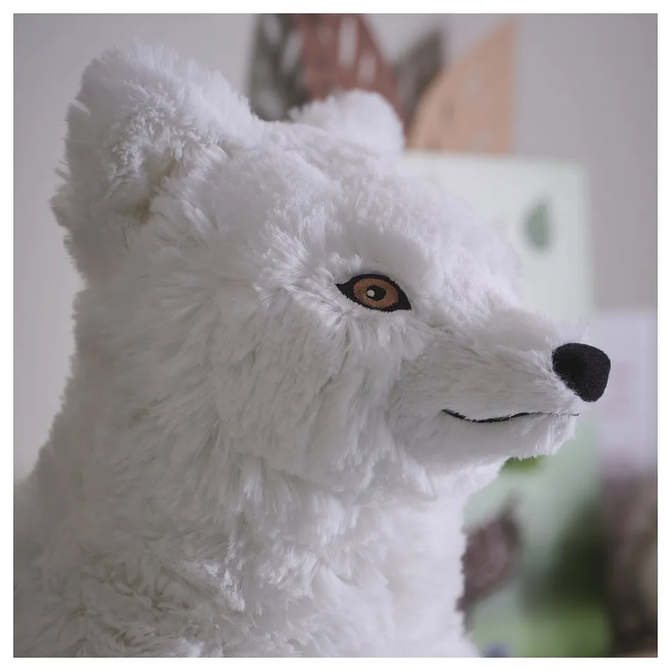 Fluffy white arctic fox cuddly toy, with detailed stitching around amber eyes and black nose, made from soft, eco-friendly materials.