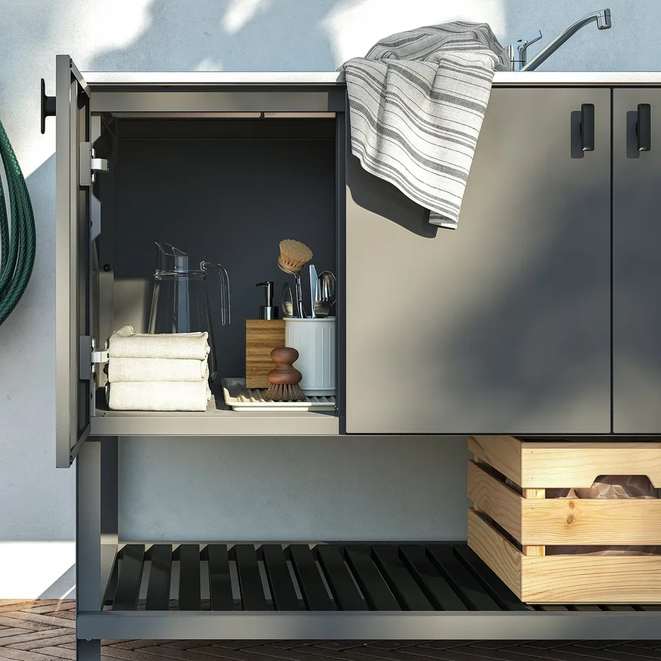 Outdoor kitchen with sink, cleaning tools, and storage.