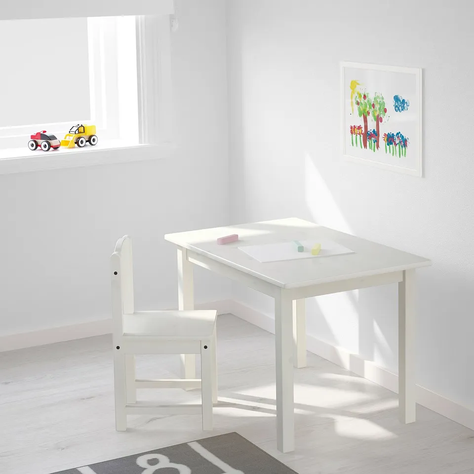 Small white kids table and chair set, ideal for drawing and crafts, with cars and art on the wall.