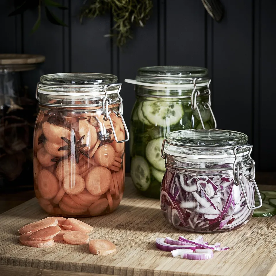 Three jars of pickled veggies and onions on wood.