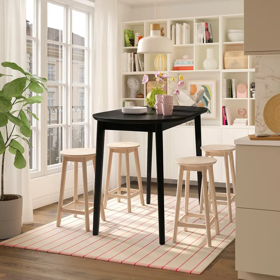 Modern black table, four light wood stools, bright interior, large window.