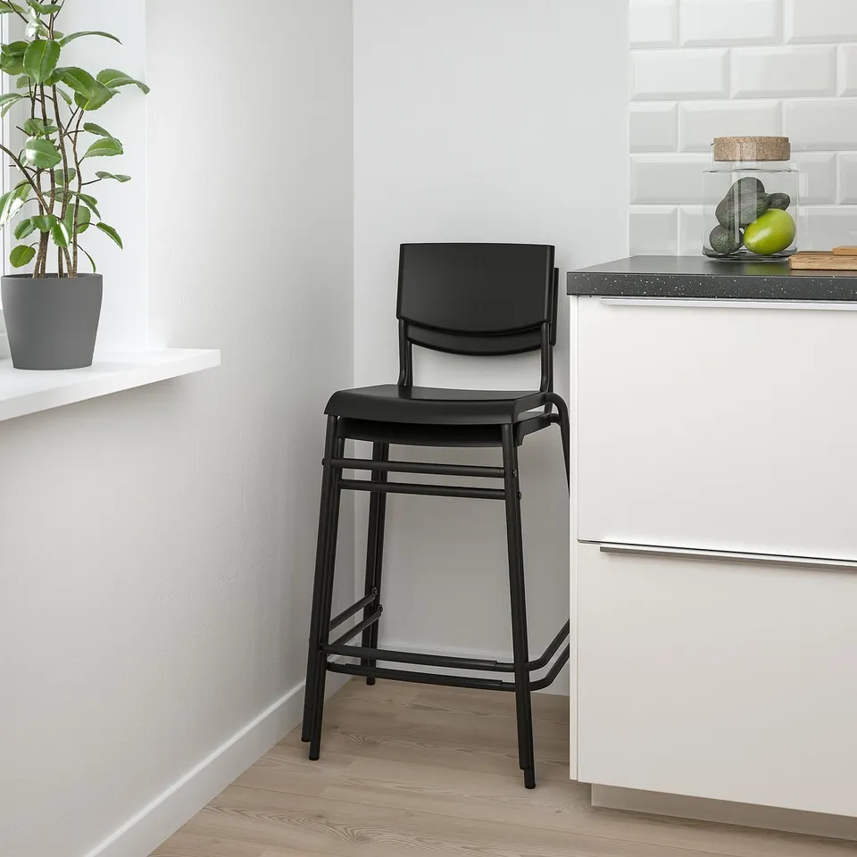 Black bar stool against counter with plant and fruit jar. Seat and backrest for comfortable seating.