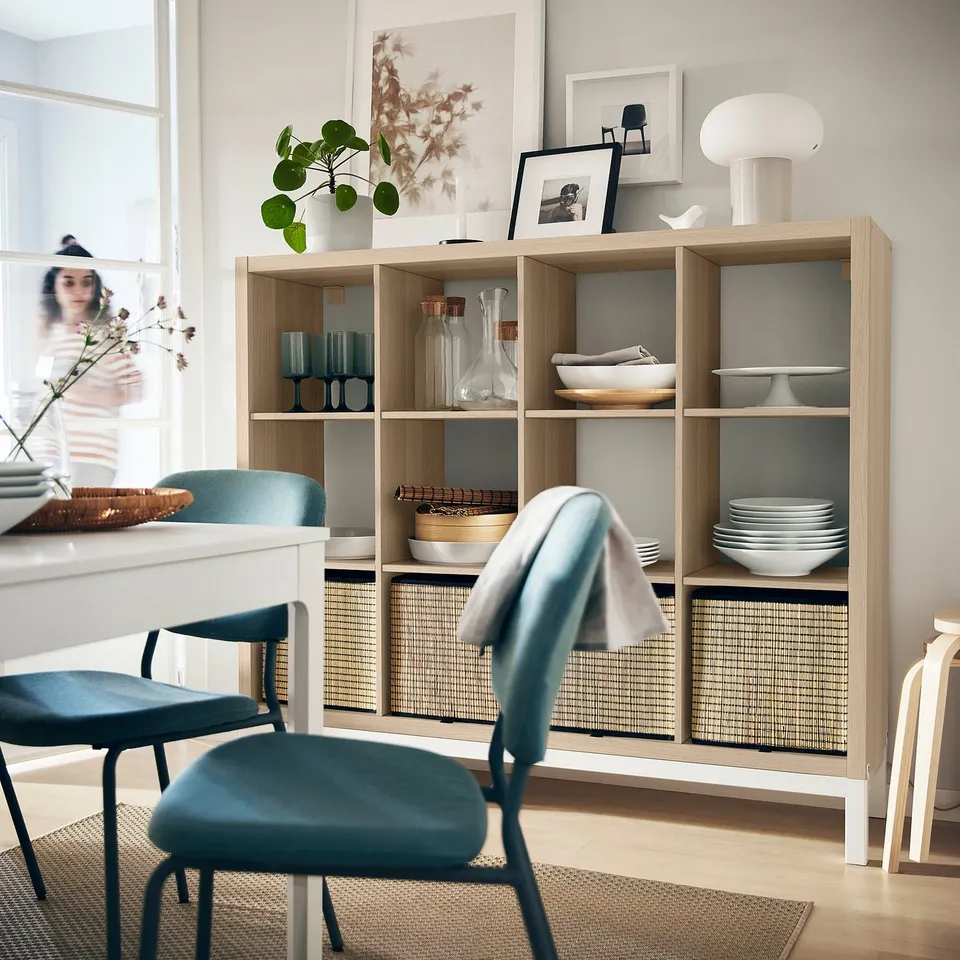 Modern living room with light wood KALLAX shelving unit. Blue chairs and various decorative items.