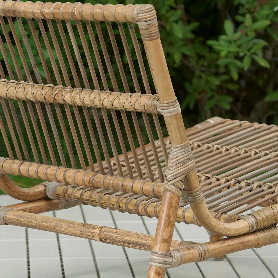 Handwoven rattan chair; intricate craftsmanship, natural material, outdoor setting.