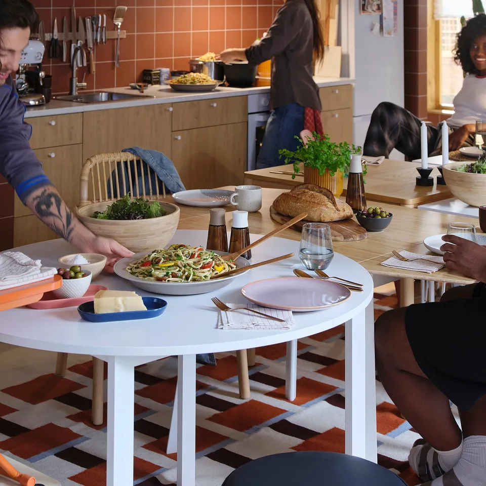 People sharing a meal around a table with HALVTOM spice jars, displaying them prominently and using them to season food.