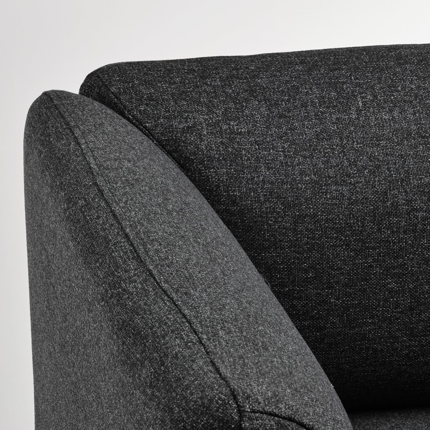 Dark grey upholstered sofa corner, smooth fabric, clean lines.